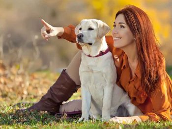 young woman teaching her labrador